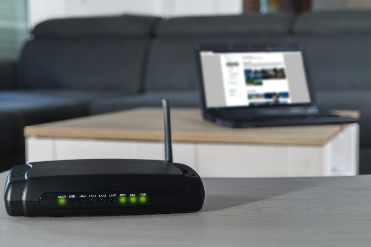Home internet connection. A wlan router on desk with notbook in background.